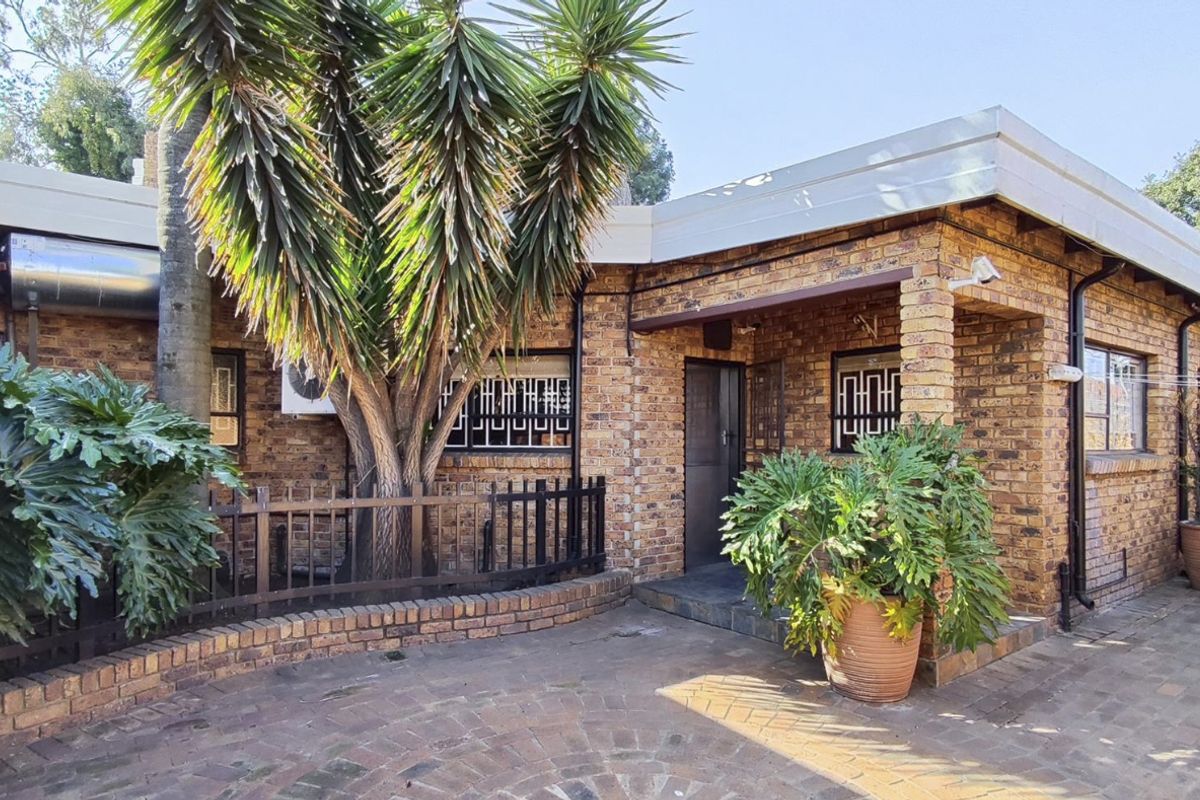 Rear exterior view of a face brick house featuring a paved patio area, security bars on windows, and an external geyser installation.