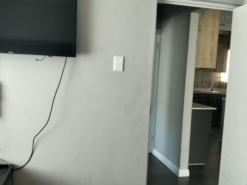 A bedroom view featuring tiled flooring and a doorway leading to an adjacent kitchen area.