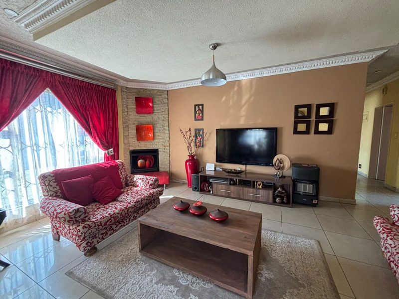 A living room featuring tiled flooring, a built-in fireplace with stone cladding, and decorative ceiling cornices, providing a functional and comfortable living space.