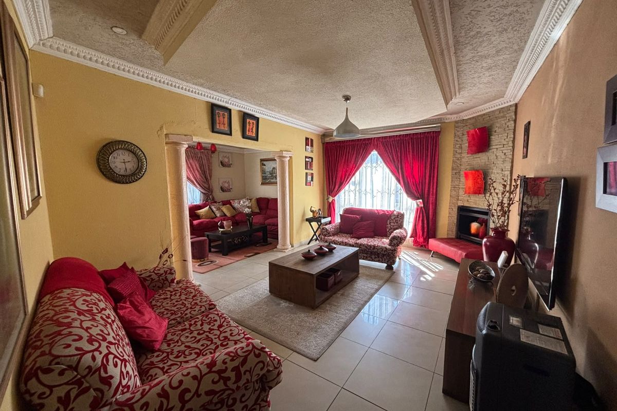 Spacious living area featuring a built-in fireplace with stone cladding, decorative ceiling molding, and tiled flooring, offering a warm and traditional layout.