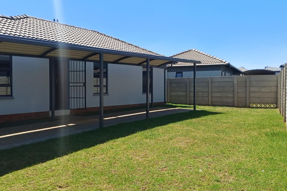 A well-maintained rear exterior featuring a covered patio, paved walkway, and a private garden enclosed by precast concrete boundary walls.