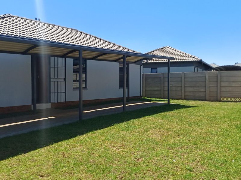 A well-maintained rear exterior featuring a covered patio, paved walkway, and a private garden enclosed by precast concrete boundary walls.