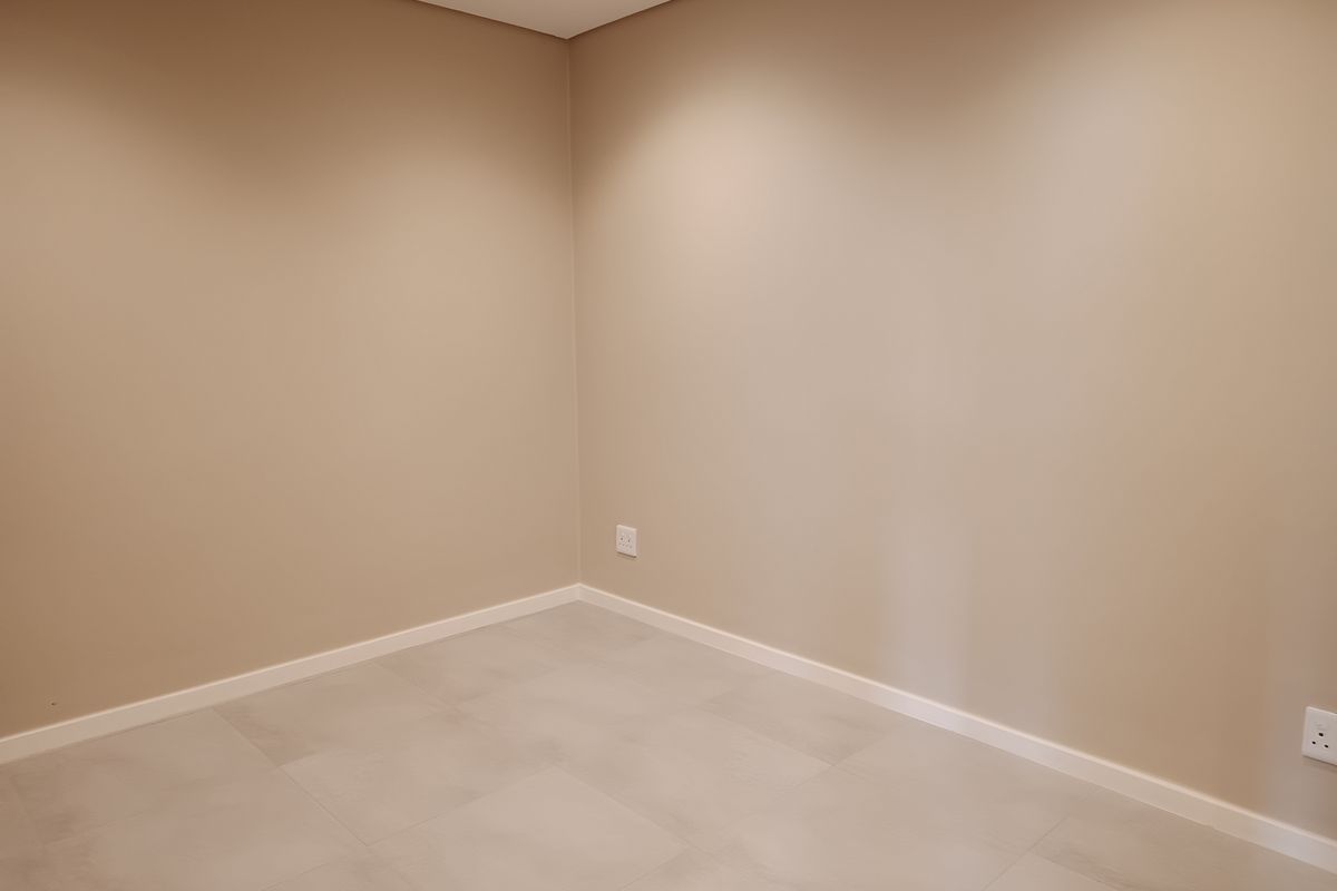 A clean, empty bedroom featuring neutral painted walls, modern tiled flooring, and recessed ceiling lighting.