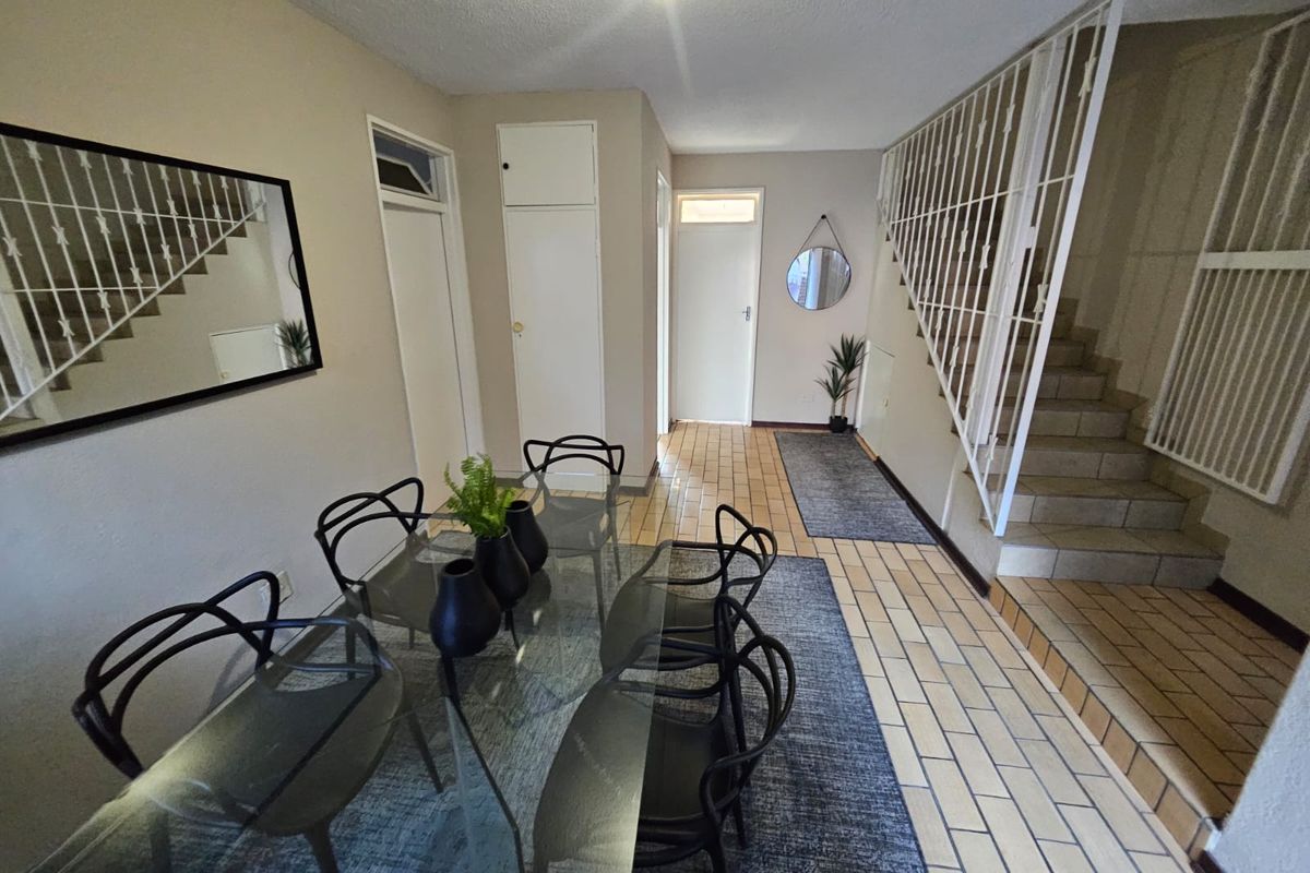 Open plan living area featuring tiled flooring, a built-in storage cupboard, and a staircase with a metal balustrade.