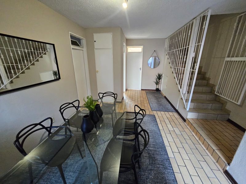 Open plan living area featuring tiled flooring, a built-in storage cupboard, and a staircase with a metal balustrade.