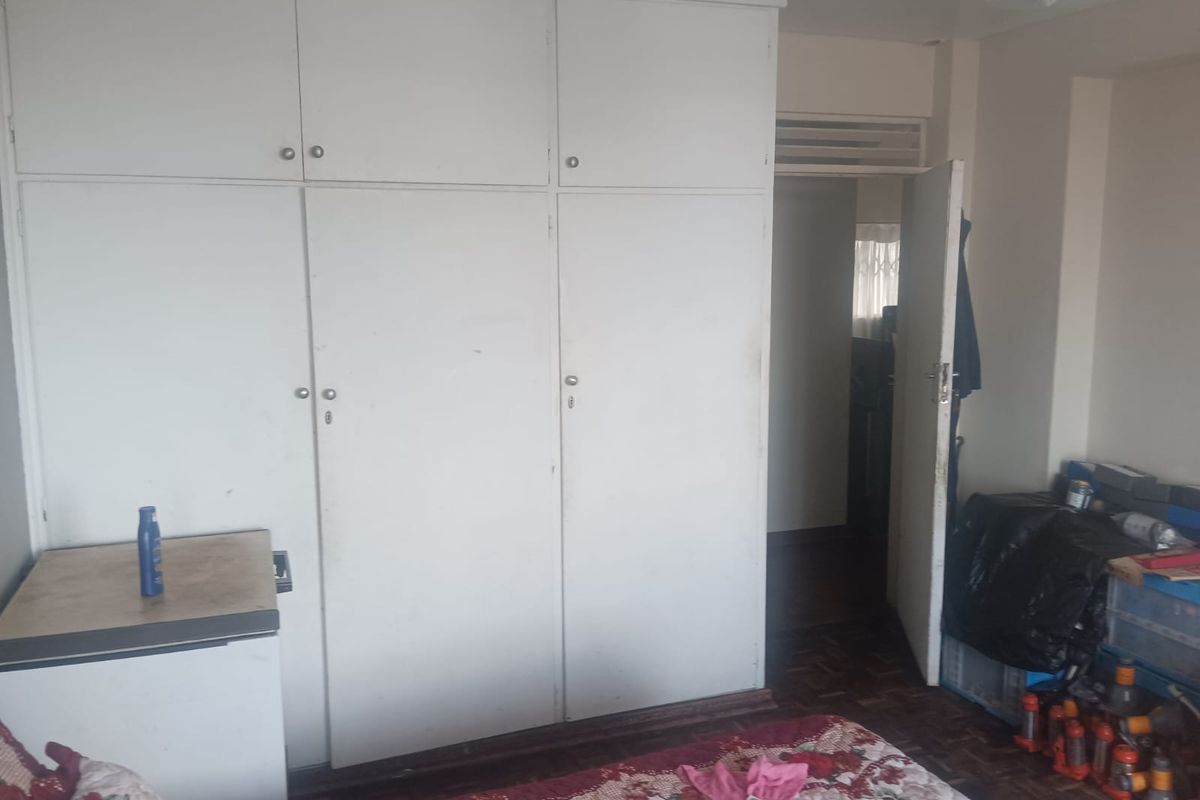 Bedroom featuring built-in cupboards and parquet flooring, requiring cosmetic updates to improve the overall aesthetic and condition of the space.