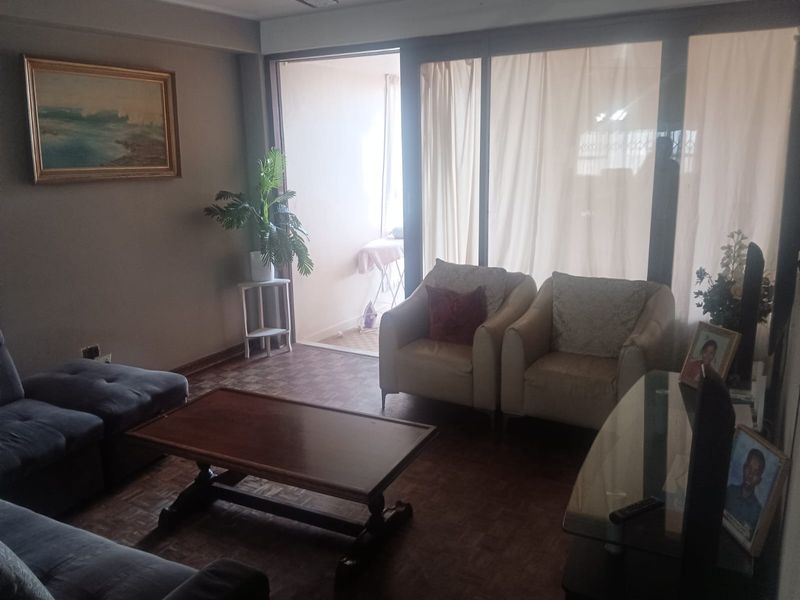 A living room featuring parquet flooring and large sliding glass doors that provide access to an adjoining balcony area.