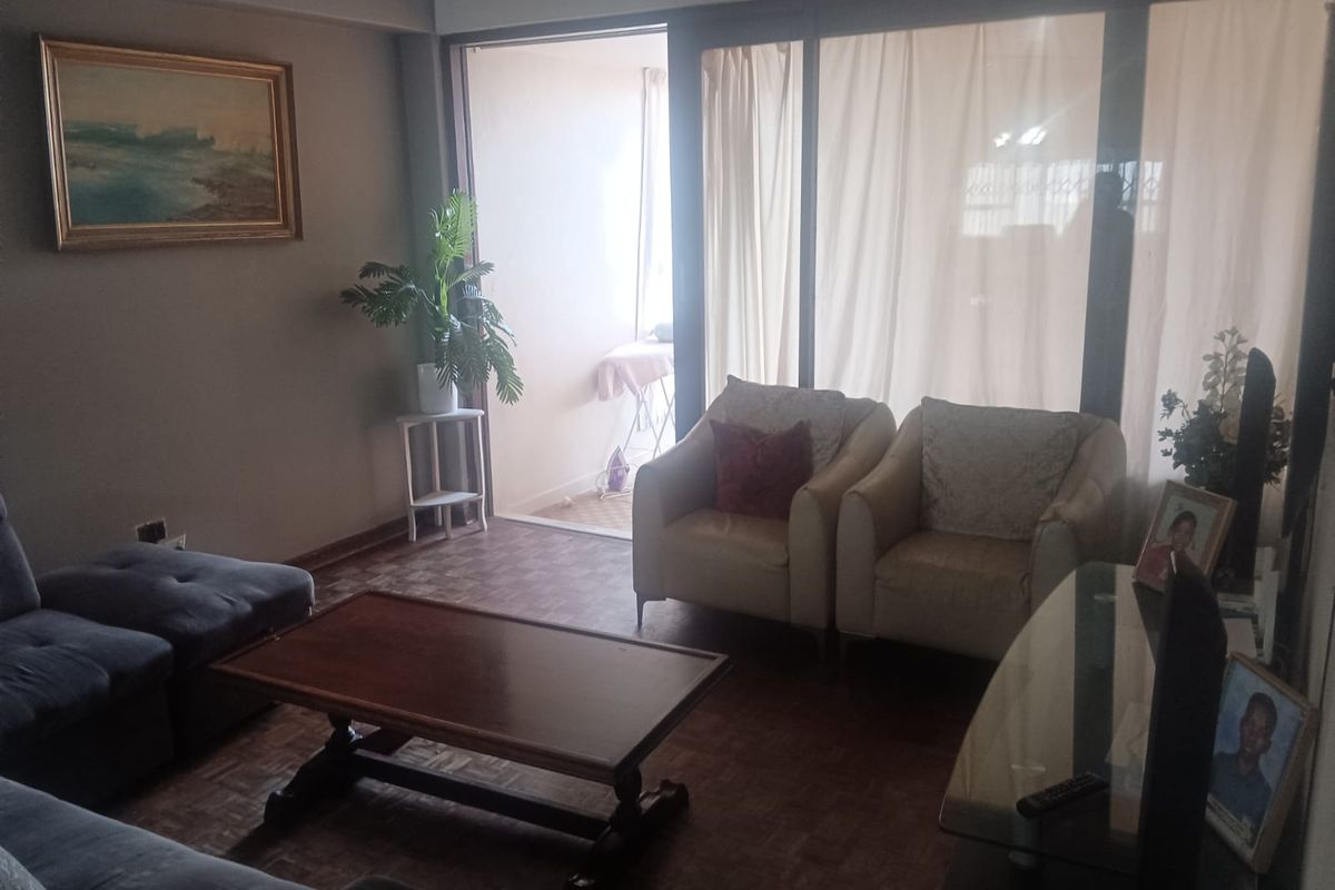 A living room featuring parquet flooring and large sliding glass doors that provide access to an adjoining balcony area.