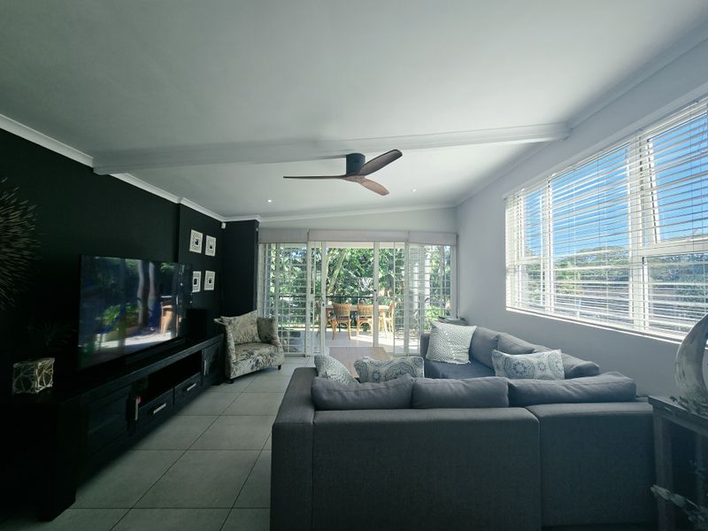 Spacious living room featuring tiled floors, a modern ceiling fan, and large sliding glass doors that provide natural light and access to the patio.