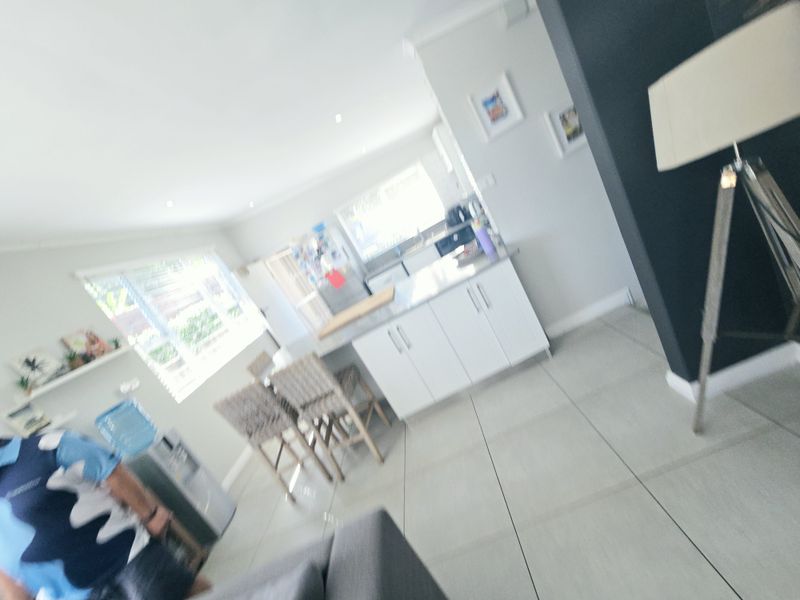 An open-plan living and kitchen area featuring modern white cabinetry, a central island, and tiled flooring throughout.