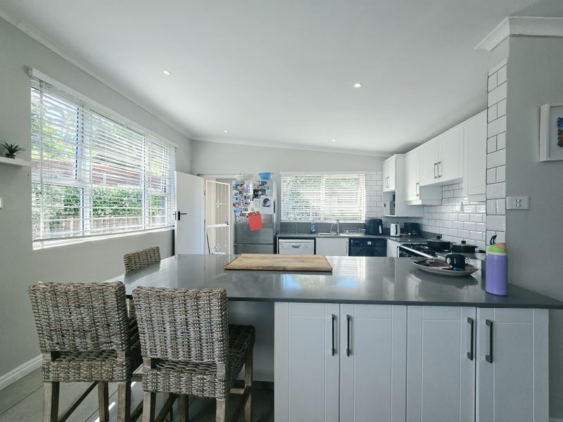 Modern kitchen featuring a central island with quartz countertops, white cabinetry, subway tile backsplash, and ample natural light from large windows.