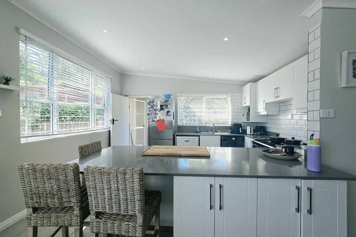 Modern kitchen featuring a central island with quartz countertops, white cabinetry, subway tile backsplash, and ample natural light from large windows.