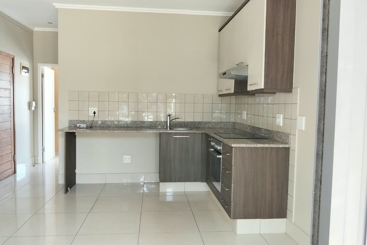 A clean, modern kitchen featuring built-in cabinetry, granite countertops, a tiled backsplash, and integrated appliances, offering a functional and well-maintained cooking space.