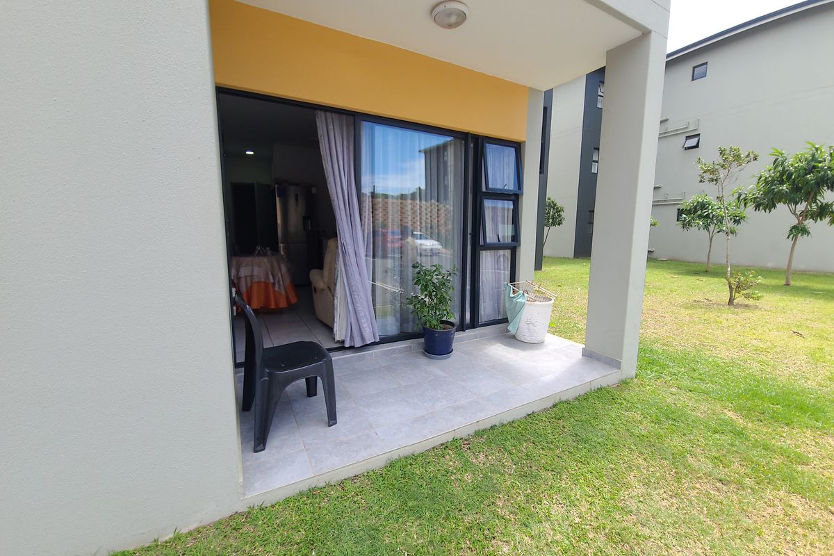 A covered ground-floor patio with tiled flooring, providing direct access to the interior living space through a sliding glass door.