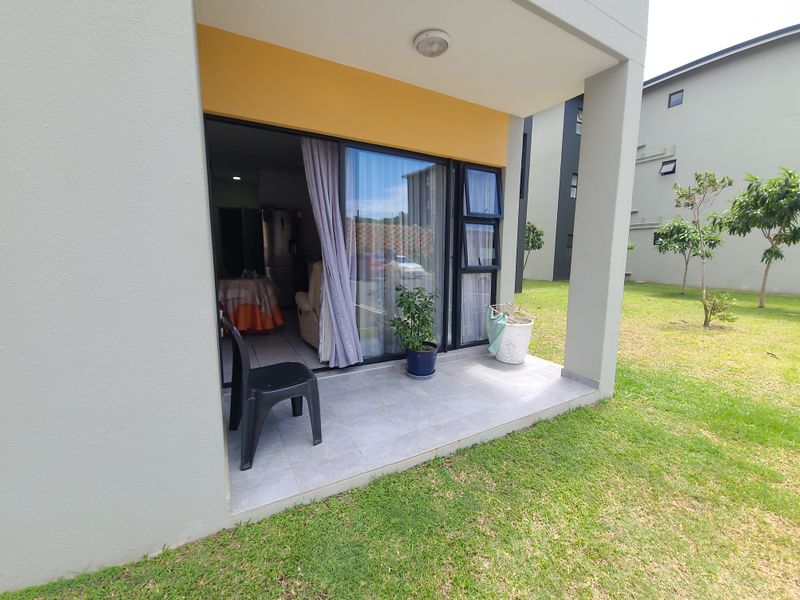 A covered ground-floor patio with tiled flooring, providing direct access to the interior living space through a sliding glass door.