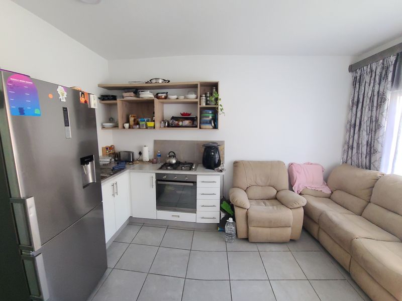 Open-plan living area featuring a compact kitchen with built-in oven, gas hob, and modern cabinetry, seamlessly integrated with the lounge space.