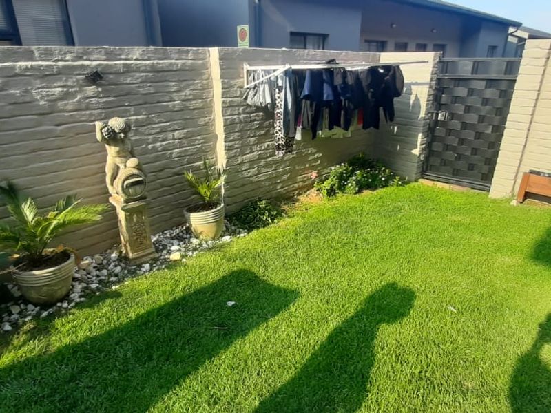 A private rear garden featuring a well-maintained lawn, secure precast concrete boundary walls, and a functional wall-mounted clothesline.