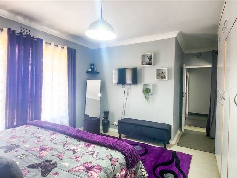 A well-maintained bedroom featuring built-in cupboards, cove cornicing, and neutral wall finishes, providing a comfortable and functional living space.