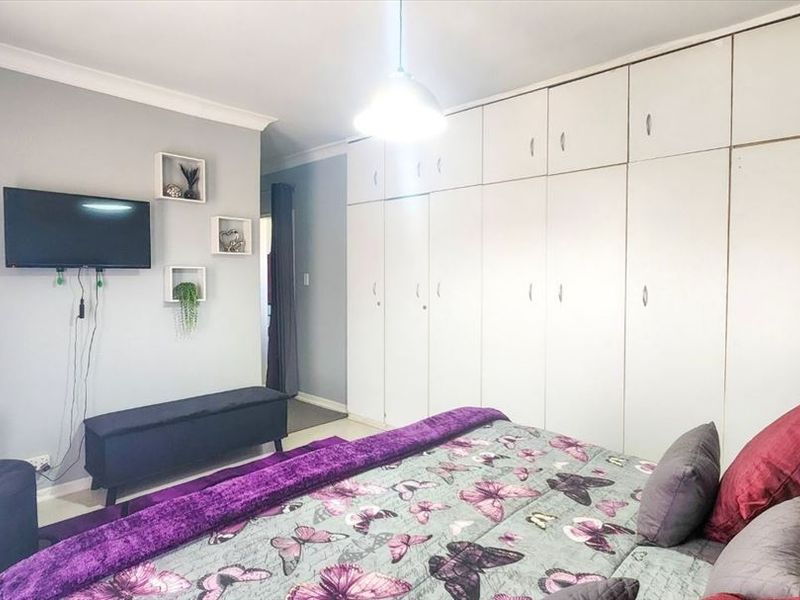A bedroom featuring extensive floor-to-ceiling built-in cupboards, neutral wall finishes, and cove cornicing, providing ample storage space.