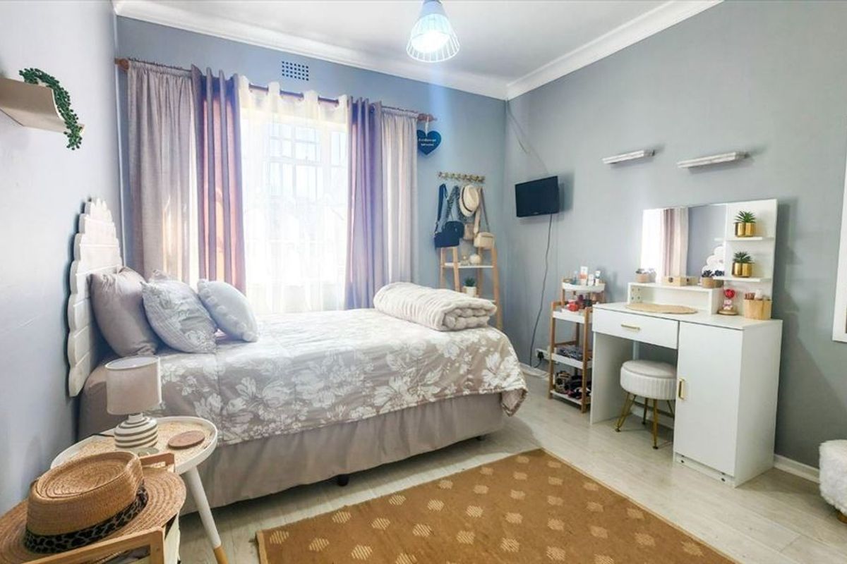 A well-maintained bedroom featuring light grey walls, laminate flooring, and decorative coving, providing a comfortable and functional living space.