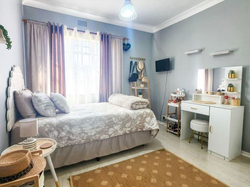 A well-maintained bedroom featuring light grey walls, laminate flooring, and decorative coving, providing a comfortable and functional living space.