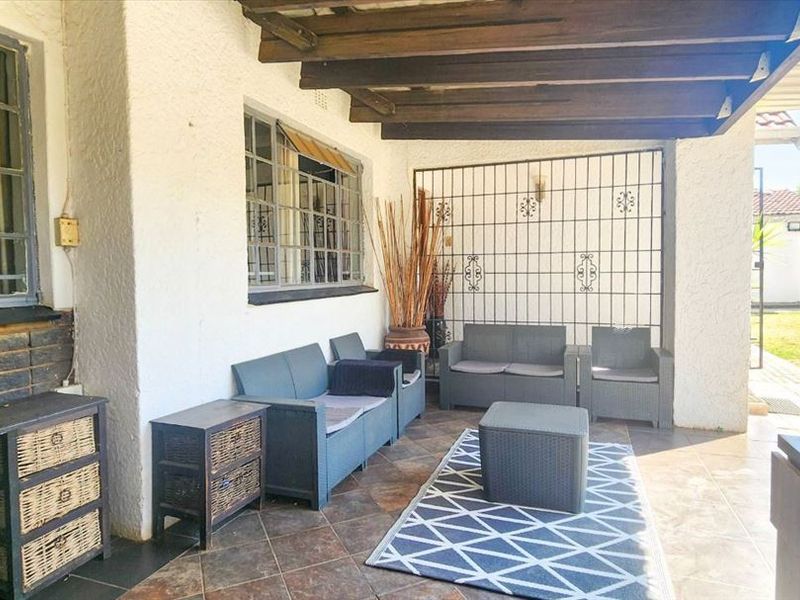 A covered patio area featuring exposed timber rafters, tiled flooring, and secure metal screening, providing a functional outdoor living space.