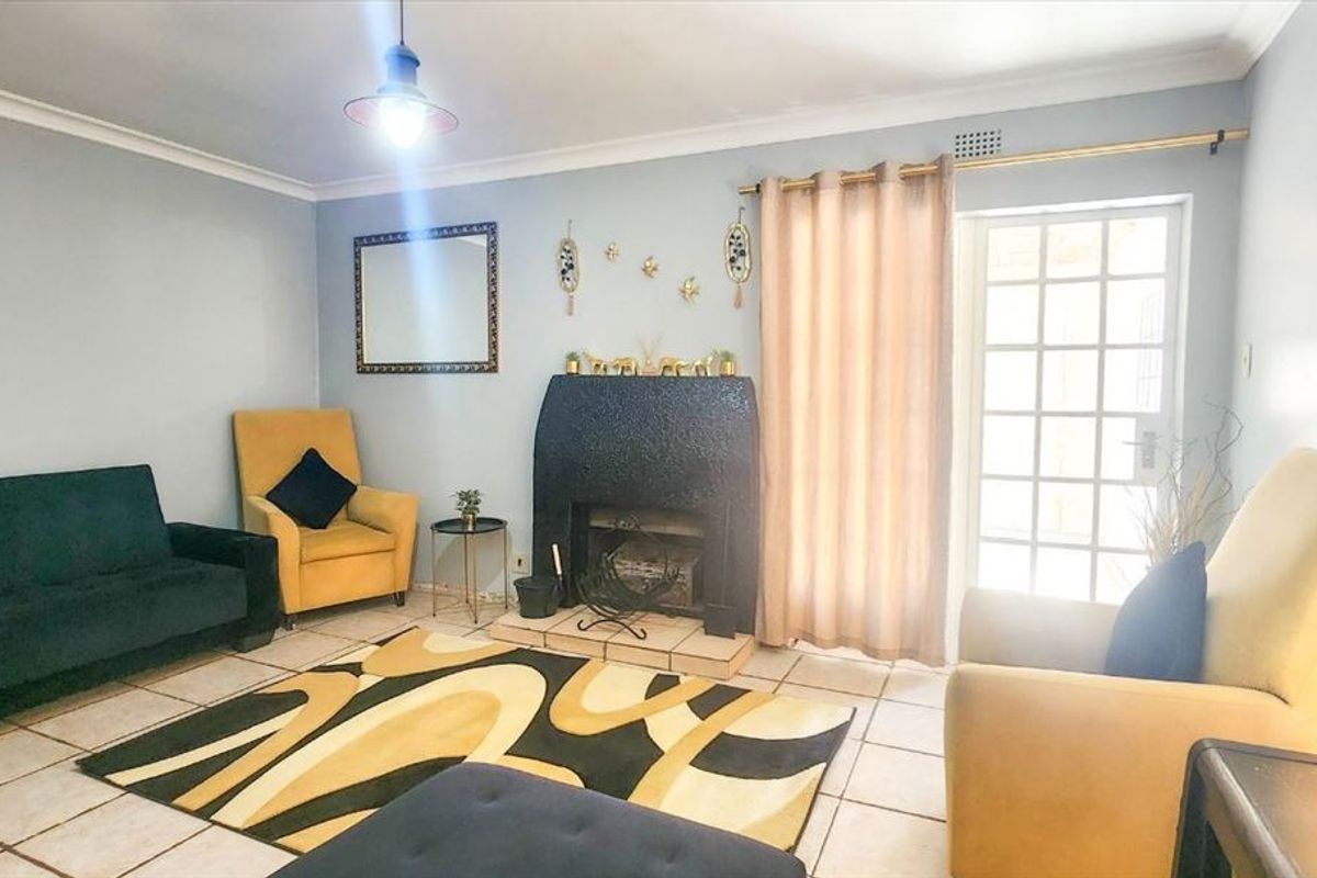 A living room featuring a prominent fireplace, tiled flooring, and a glass panel door providing access to the exterior.