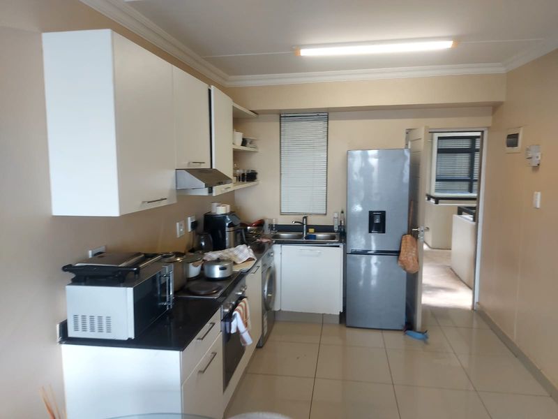 A functional kitchen featuring white cabinetry, granite countertops, integrated oven and hob, and tiled flooring, providing a practical workspace for daily cooking.
