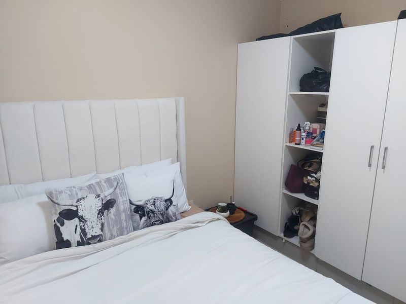 A bedroom featuring a built-in wardrobe with open shelving and closed storage compartments.