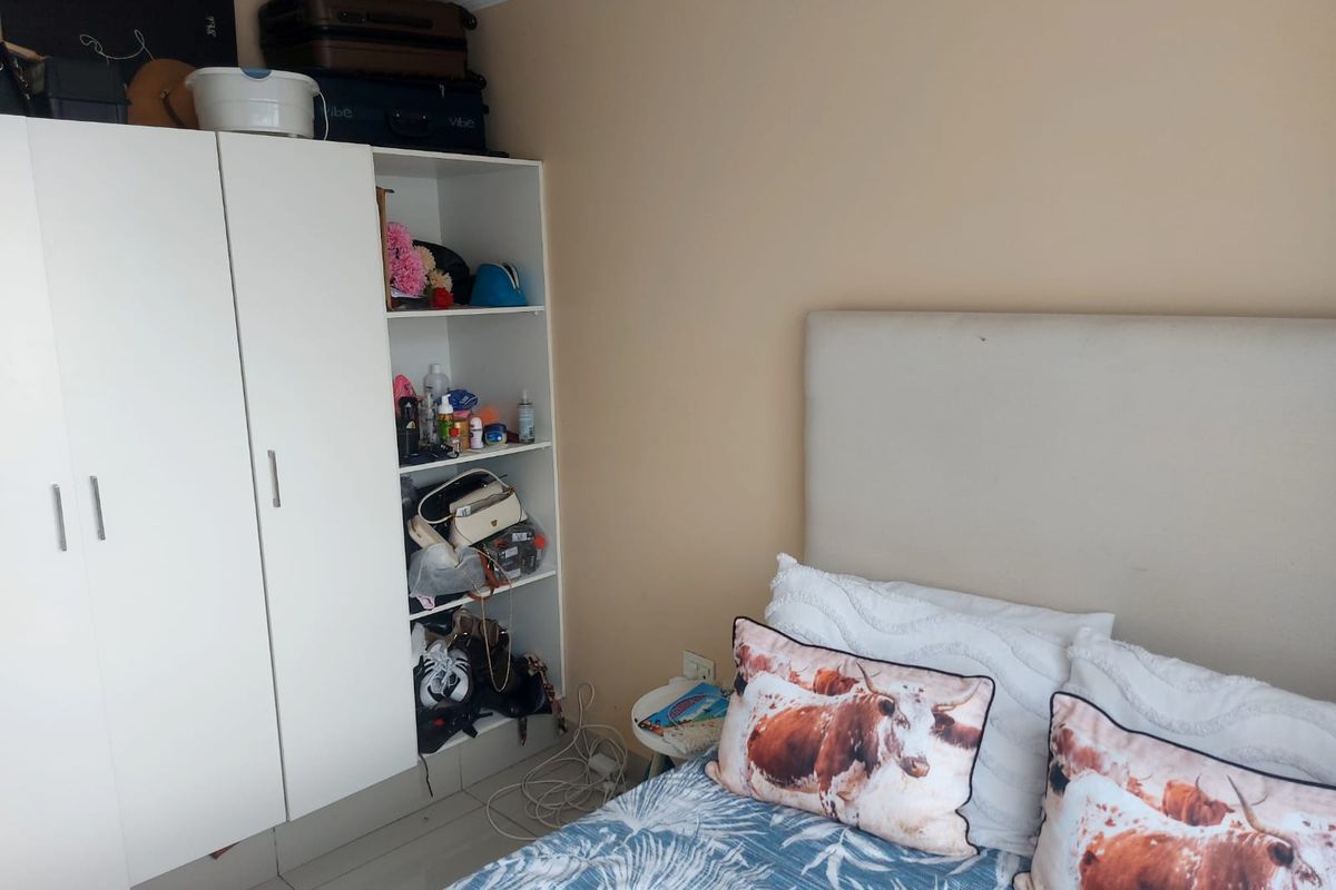 A bedroom featuring a built-in white wardrobe with open shelving and tiled flooring.