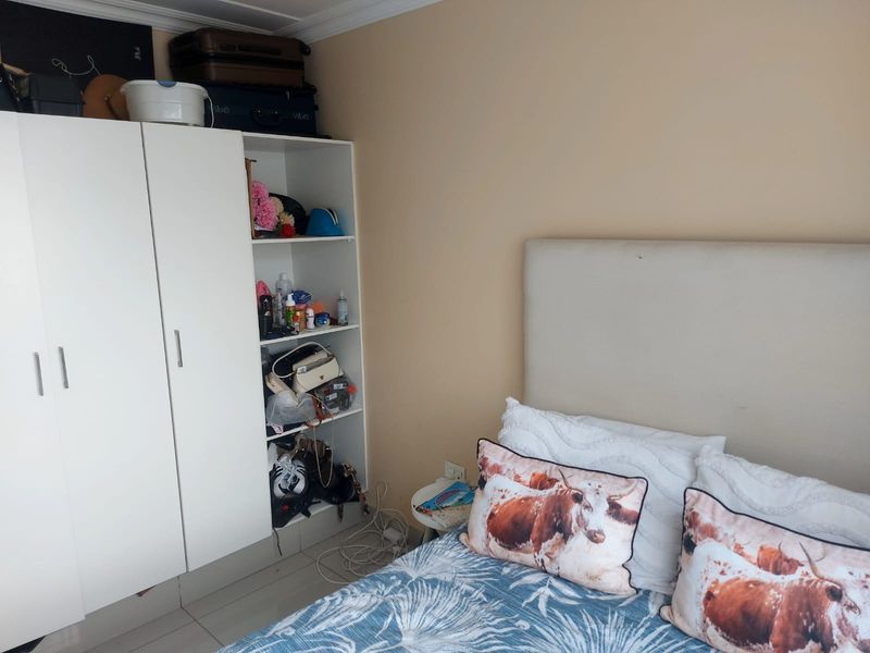 A bedroom featuring a built-in white wardrobe with open shelving and tiled flooring.