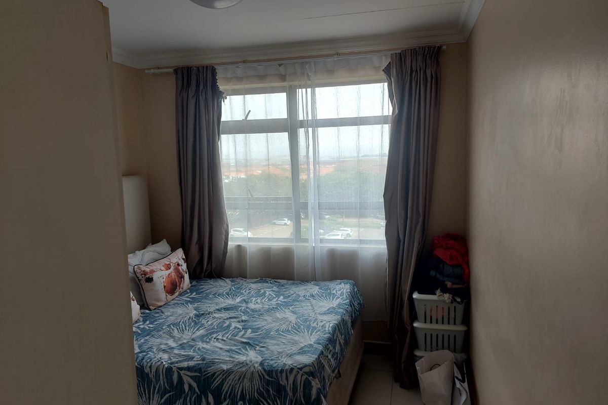 A compact bedroom featuring tiled flooring and a large window that provides natural light and an exterior view.