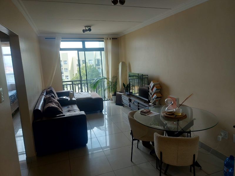 Open plan living and dining area featuring tiled flooring and a large sliding glass door leading to a balcony.