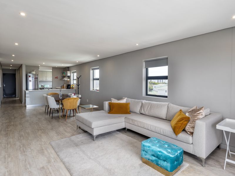 Spacious open-plan living and dining area featuring modern laminate flooring, recessed lighting, and a contemporary kitchen with integrated cabinetry.