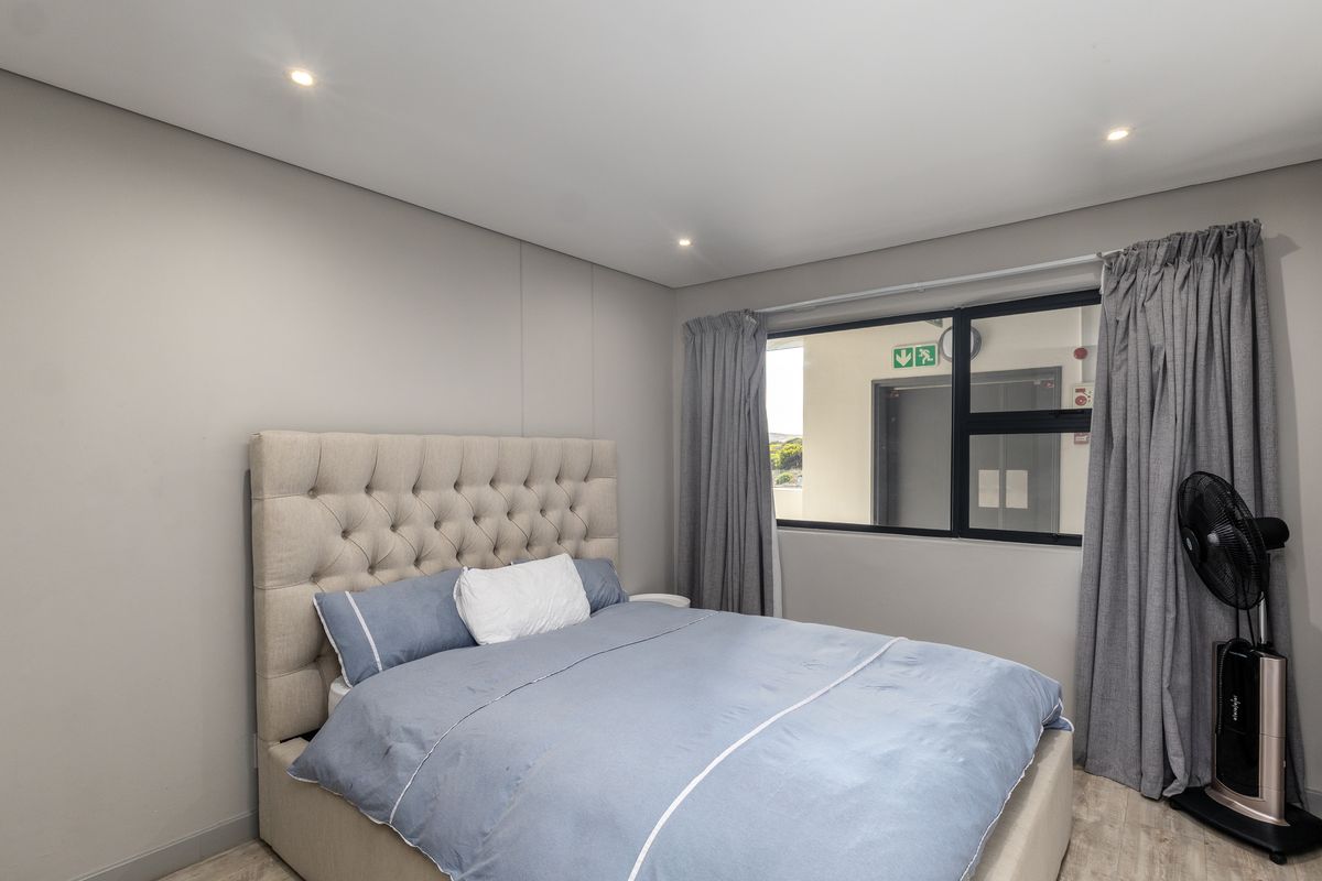 A well-maintained bedroom featuring neutral wall tones, recessed downlighting, and modern laminate flooring, offering a clean and comfortable living space.