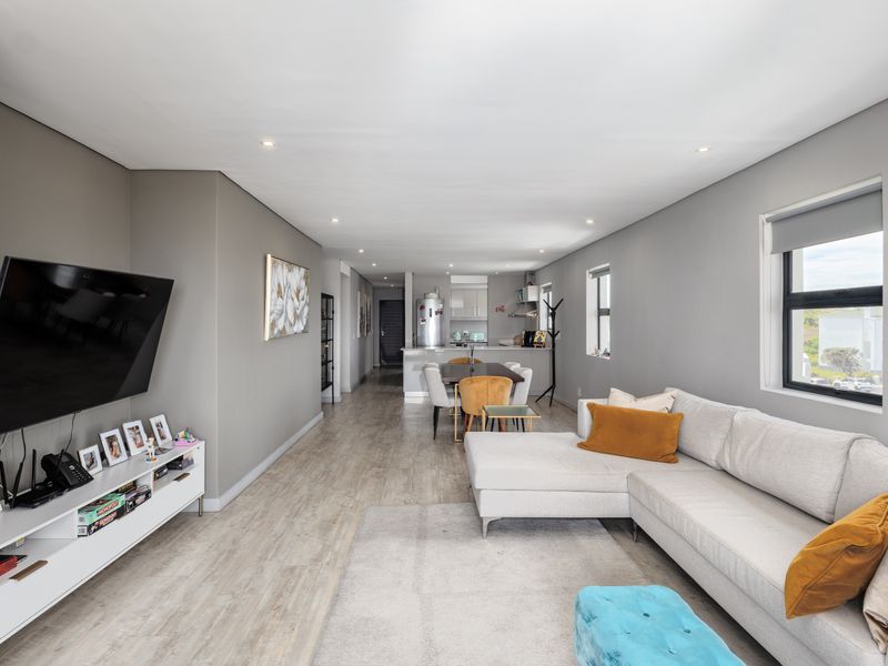 Spacious open-plan living and dining area featuring modern laminate flooring, recessed lighting, and a functional kitchen with island cabinetry.