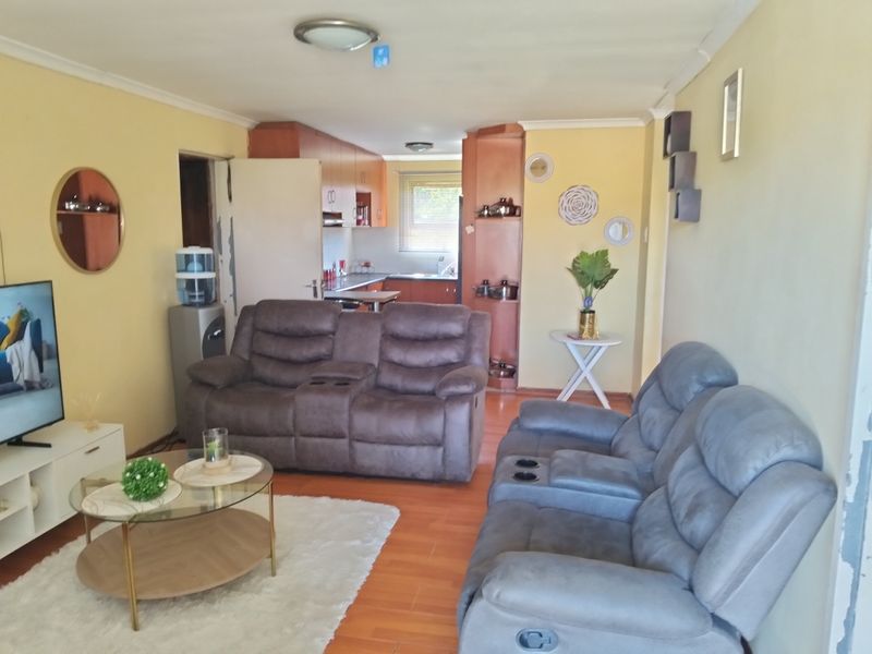 Open plan living area featuring laminate flooring and a connected kitchen space with built-in cabinetry.