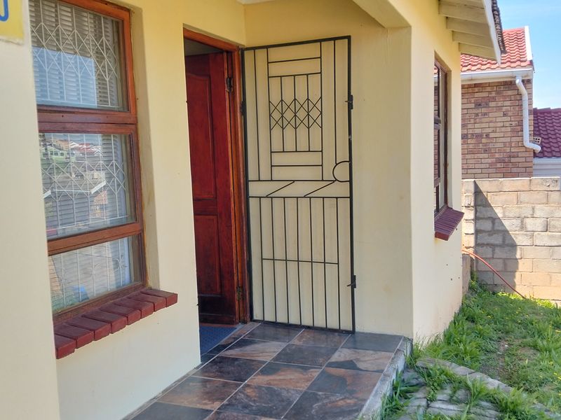 Front entrance area featuring a tiled patio, security gate, and timber window frames with brick sills.