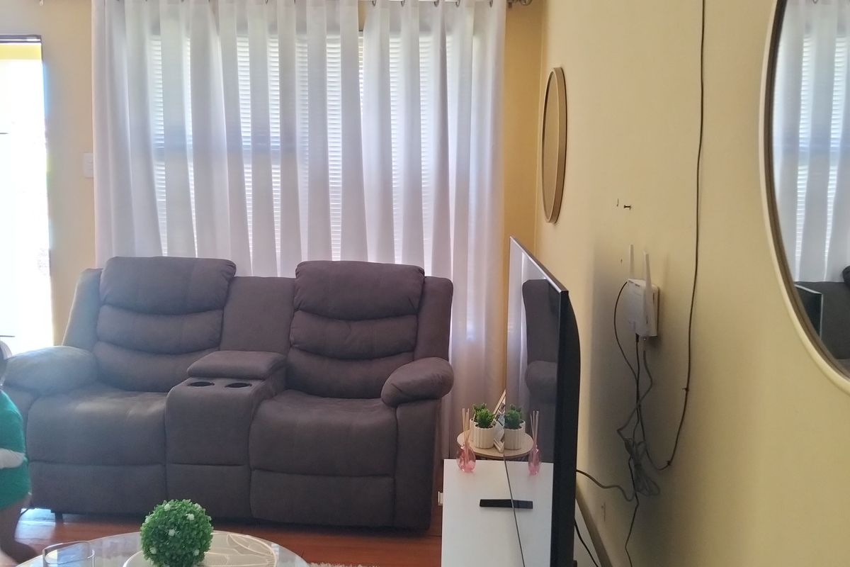 A living room featuring timber flooring and cove cornicing, currently showing visible wall surface damage and exposed wiring.