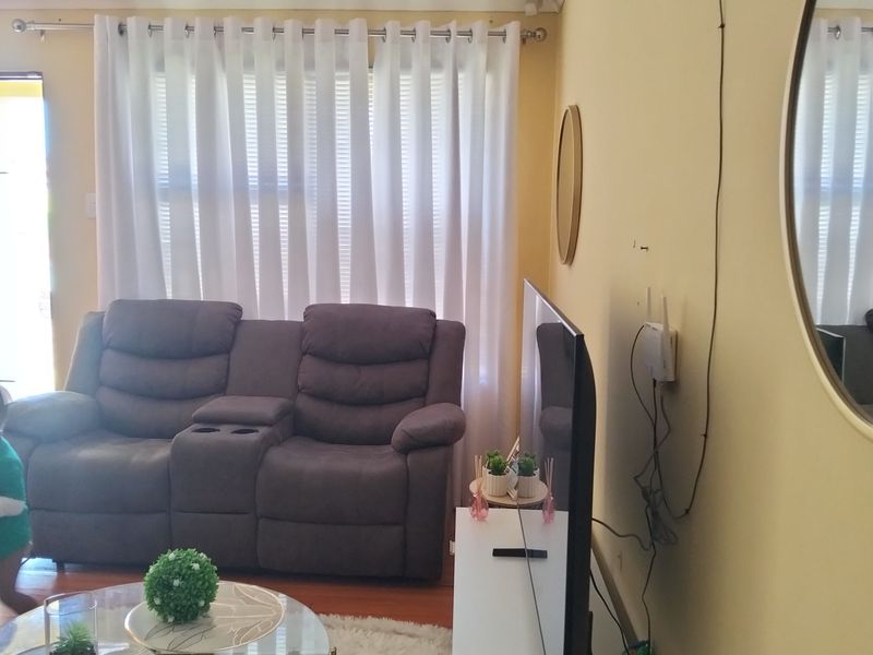 A living room featuring timber flooring and cove cornicing, currently showing visible wall surface damage and exposed wiring.