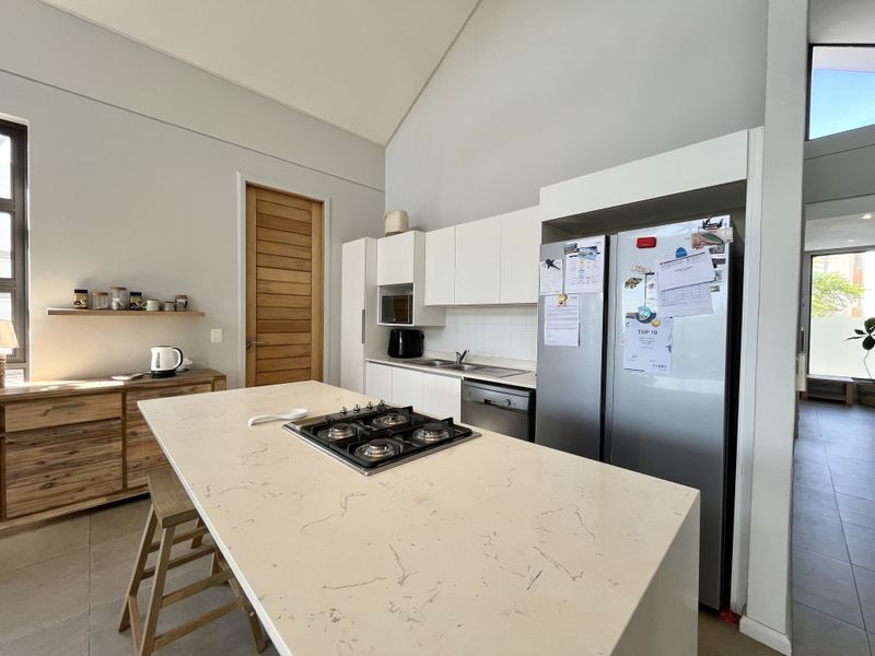 Modern kitchen featuring a central island with a gas hob, ample cabinetry, and a high vaulted ceiling, creating a bright and spacious cooking area.