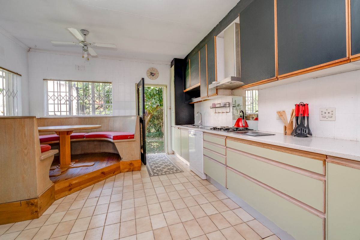 Functional kitchen featuring built-in cabinetry, gas hob, extractor fan, and a unique integrated breakfast nook with direct access to the garden.