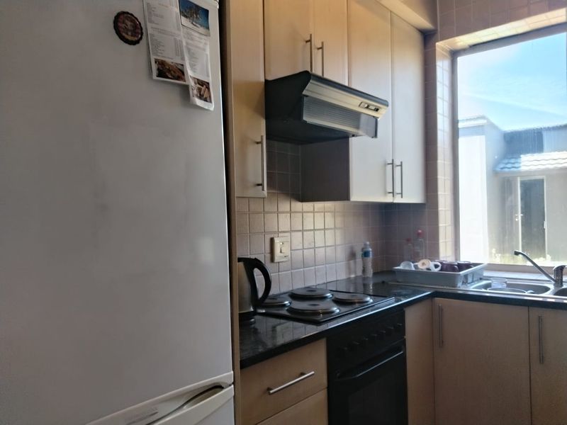 A functional kitchen featuring light wood cabinetry, granite countertops, a built-in oven with electric hob, and a tiled backsplash.