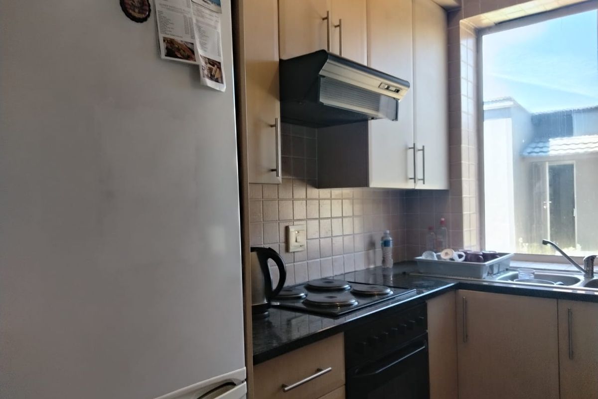 A functional kitchen featuring light wood cabinetry, granite countertops, a built-in oven with electric hob, and a tiled backsplash.