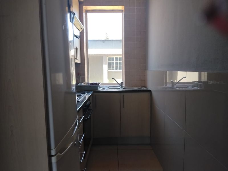 Compact scullery area featuring built-in cabinetry, a stainless steel sink, tiled splashbacks, and integrated cooking appliances.