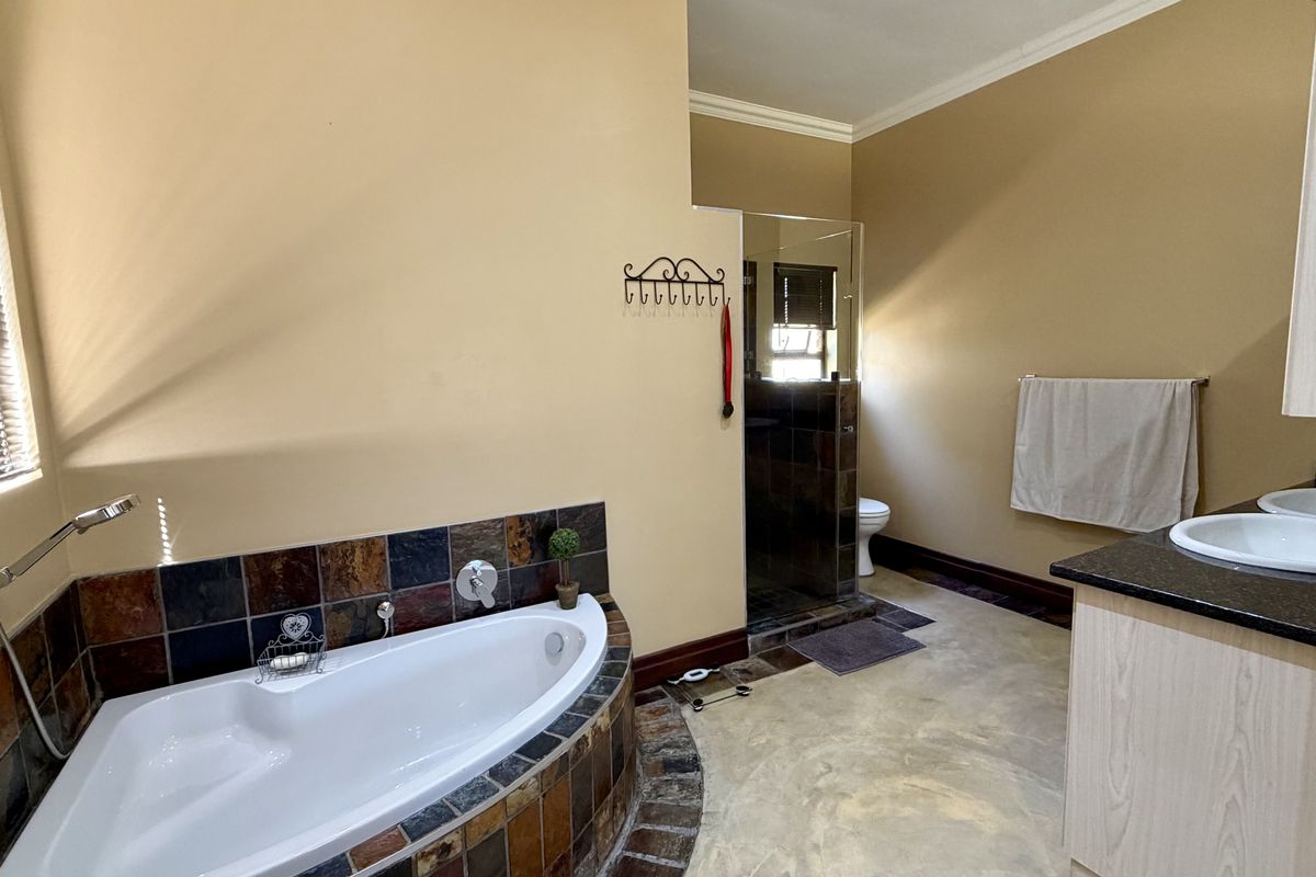 Spacious bathroom featuring a corner bathtub with tiled surround, a separate shower enclosure, and a dual vanity with granite countertops.