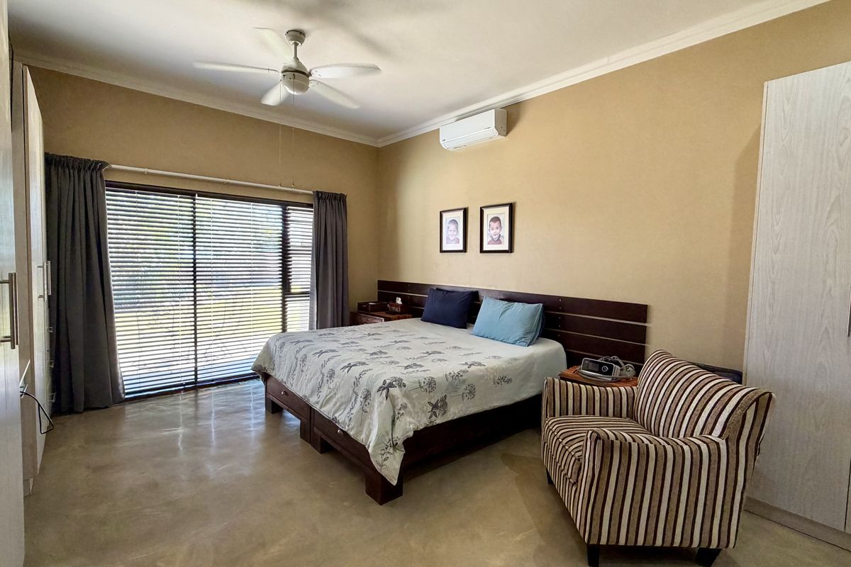 Spacious bedroom featuring polished concrete floors, built-in wardrobes, a ceiling fan, and a split-system air conditioner with access to a sliding glass door.
