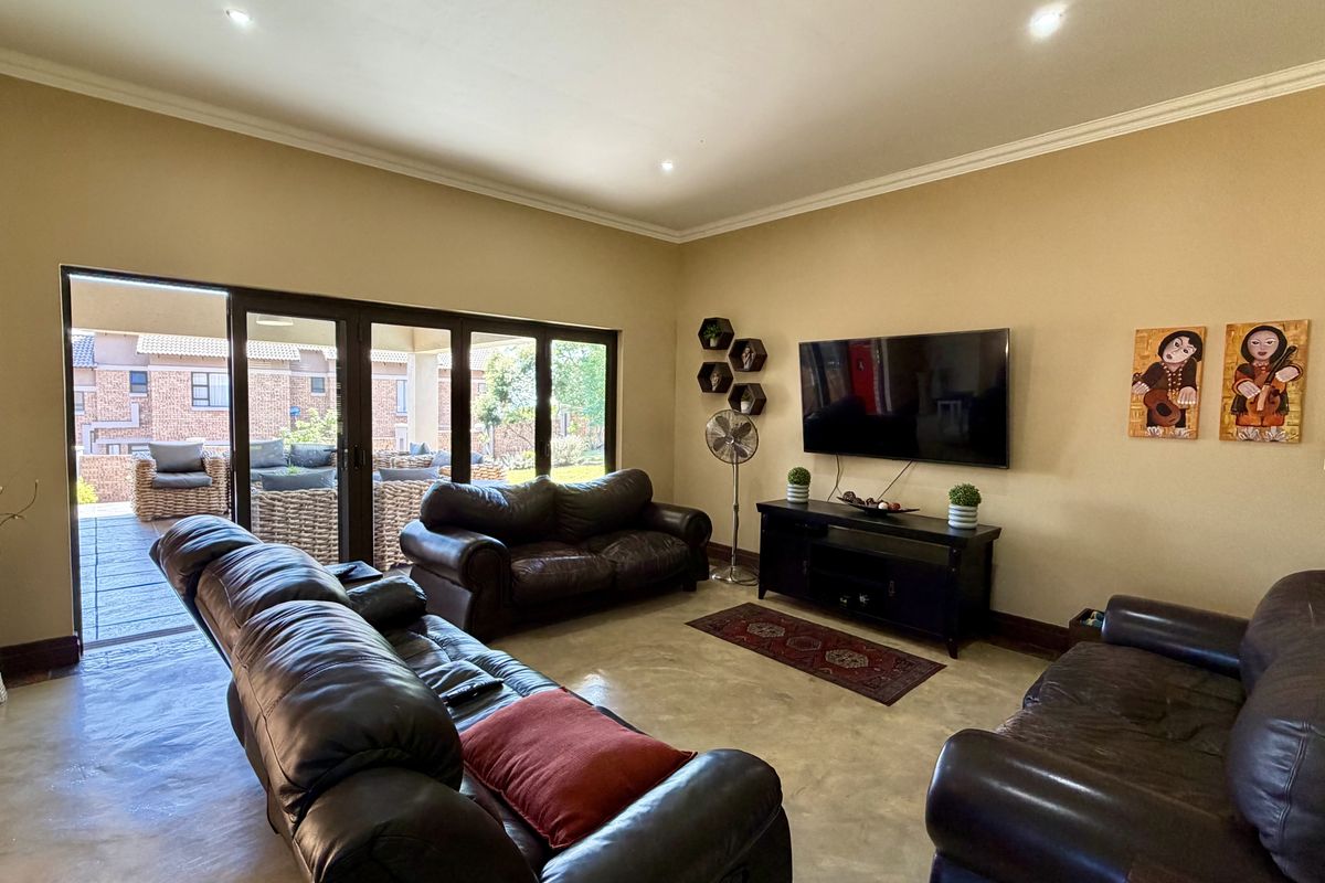 Spacious living room featuring polished concrete floors, recessed lighting, and large sliding glass doors that provide seamless access to the outdoor patio area.