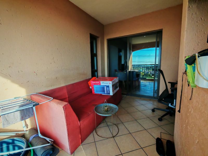 A covered balcony area featuring tiled flooring and a sliding glass door providing access to the interior living space.