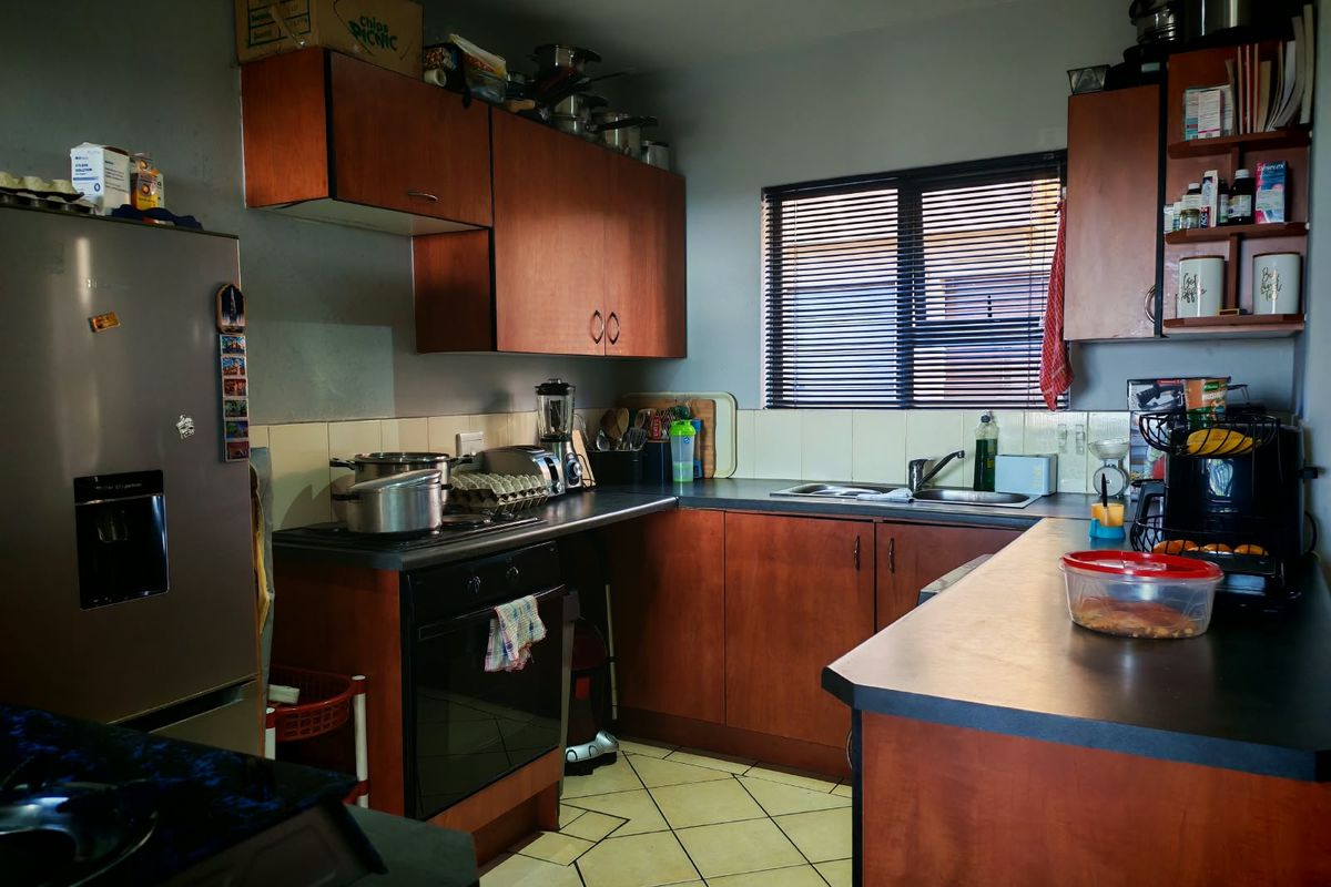 A functional kitchen featuring wood-finish cabinetry, laminate countertops, a built-in oven, and tiled flooring, offering a practical layout for daily meal preparation.